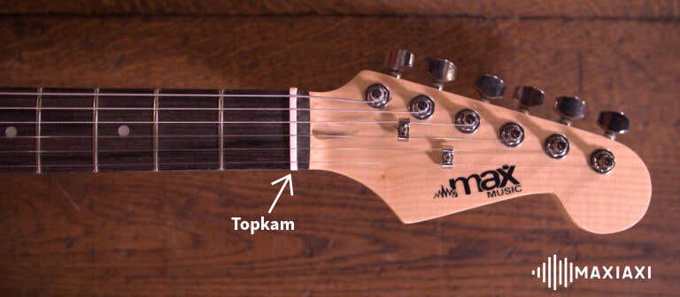 Close-up van een gitaar hals met een pijl naar de topkam