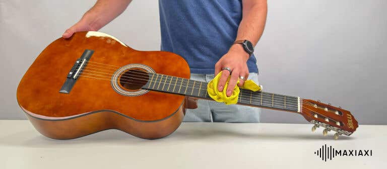 Iemand die de snaren van een gitaar schoonmaakt met een microvezeldoek