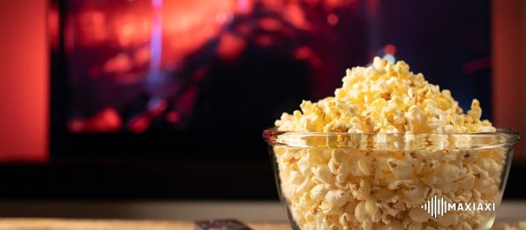 sfeerafbeelding van een bak popcorn en een film op de achtergrond