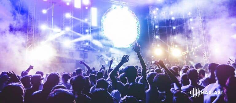 Festivalpublikum vor einer beleuchteten Bühne mit Rauch- und Lichteffekten – ausgelassene Stimmung bei einem Live-Konzert.