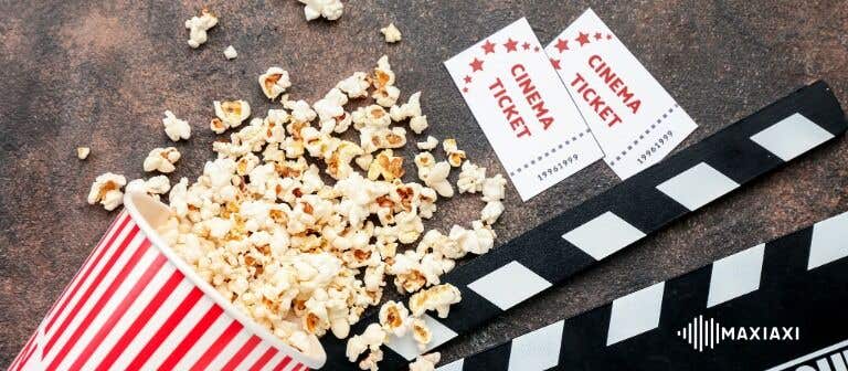 Popcorn, Filmklappe und Kinotickets auf einem Tisch als Symbol für einen Filmabend.