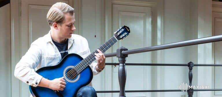Mann spielt akustische Gitarre auf einem Balkon – konzentriertes Gitarrenspiel in ruhiger Umgebung.