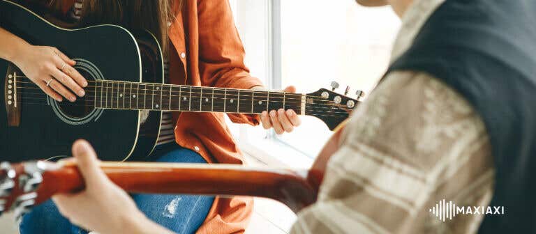 Ein Schüler und ein Gitarrenlehrer mit Akustikgitarren