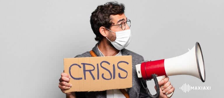 Mann mit Mundschutz hält ein Schild mit der Aufschrift ‘Crisis’ und spricht durch ein Megafon – Symbolbild für Notfall- und Krisensituationen.