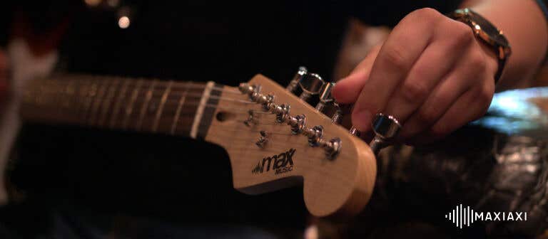 Hand stimmt die Mechaniken einer E-Gitarre – Gitarrenpflege durch korrektes Stimmen und Justieren der Saiten.
